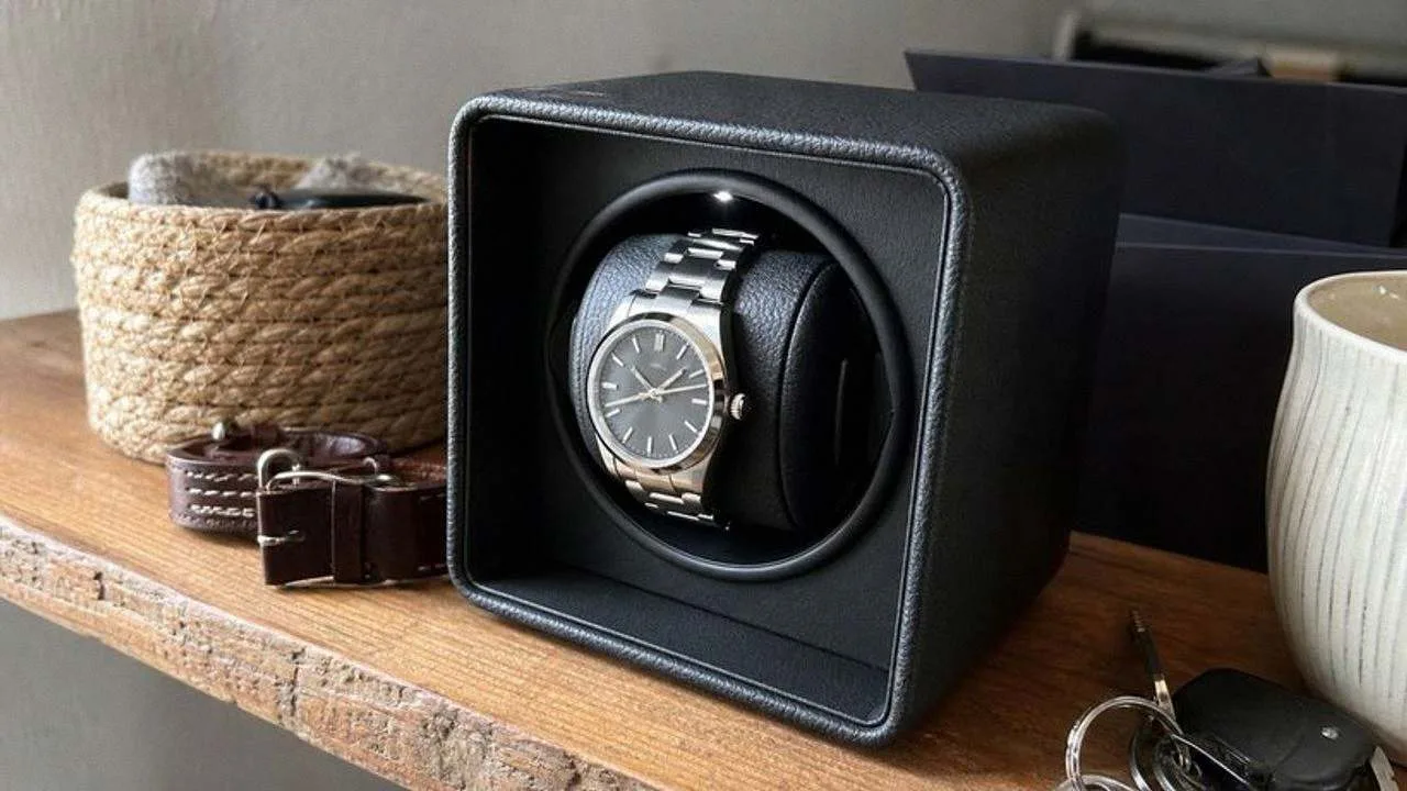 Winder individual en forma de cubo de polipiel negra con un reloj de brazalete de acero sobre el cojín giratorio